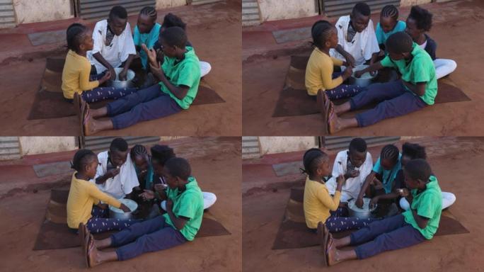 贫穷。年轻的黑人非洲儿童坐在地上用手在小镇贫民窟里吃玉米粥