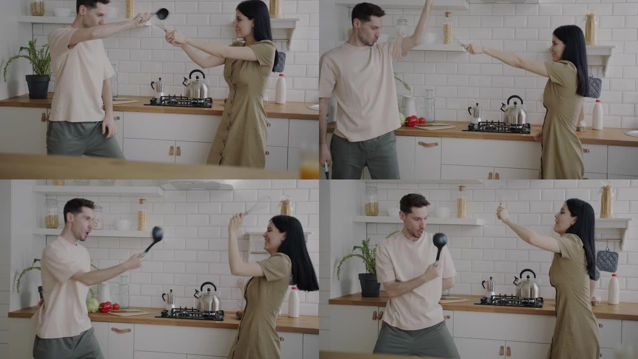 顽皮的年轻夫妇用厨具击剑笑着一起在家里玩得开心