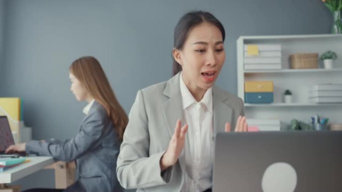 在新的正常情况下，女商人在办公室工作时使用笔记本电脑向同事介绍视频通话中的计划，以预防病毒。电晕病毒