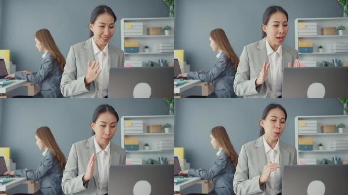 在新的正常情况下，女商人在办公室工作时使用笔记本电脑向同事介绍视频通话中的计划，以预防病毒。电晕病毒