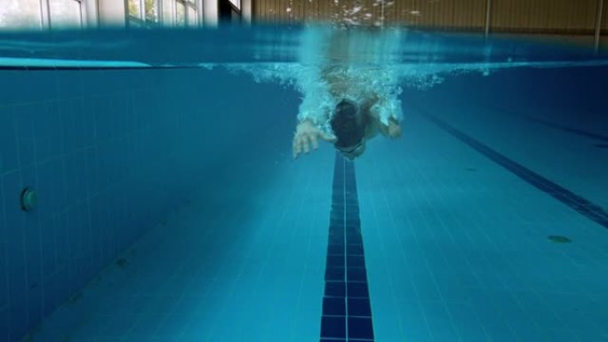 截肢者适应性运动员蝶泳在室内游泳池水下游泳