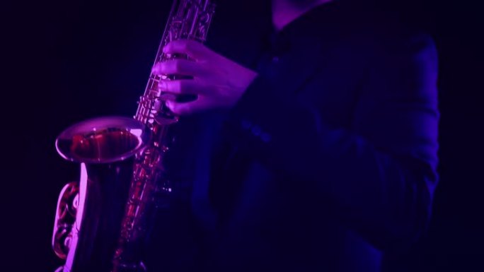 男子在五颜六色的灯光下在舞台上演奏萨克斯管