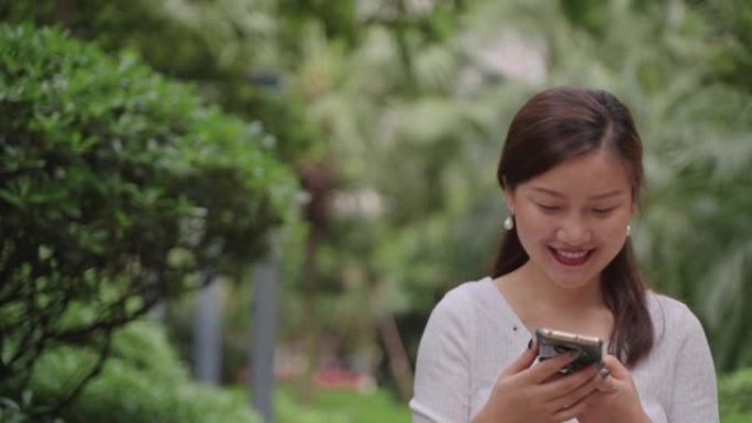 快乐的亚洲女人在公园里使用电话