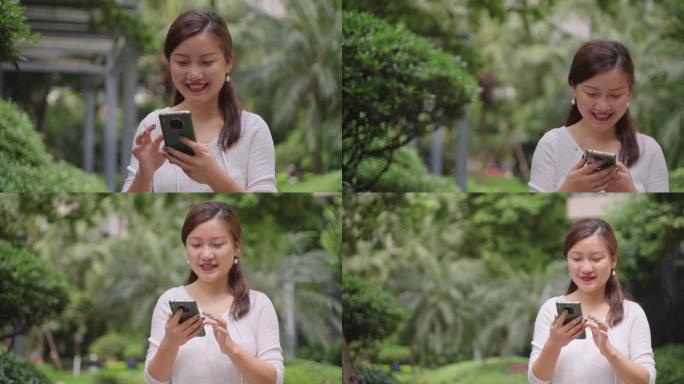 快乐的亚洲女人在公园里使用电话