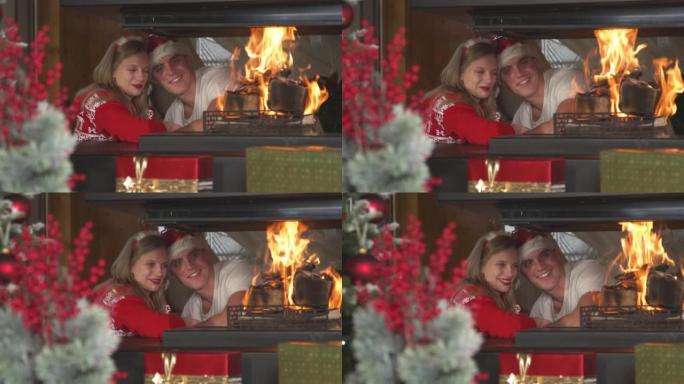 相爱的圣诞节夫妇互相靠在一起，看着燃烧的壁炉