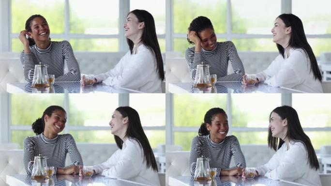两个年轻的多种族女孩最好的朋友在咖啡馆里笑，聊天
