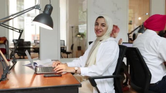 伊斯兰妇女坐在创业办公室的办公桌前