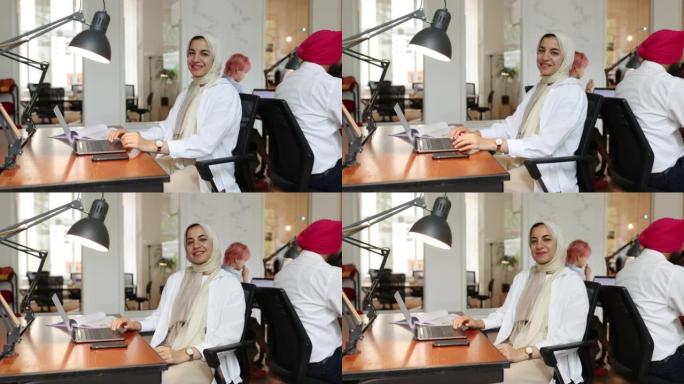 伊斯兰妇女坐在创业办公室的办公桌前