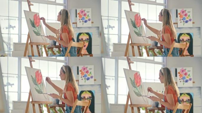 一位年轻的女画家在工作室里在画布上画彩画。严肃的女人在车间用画笔画一朵花。女人在她的美术馆里画一朵玫