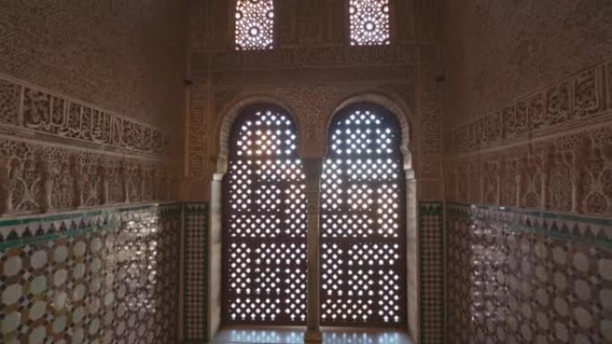 格拉纳达阿尔罕布拉宫宏伟的摩尔内部。摄像机移动到带有摩尔人装饰品的墙壁之间的窗户拱门。万向节射击，4