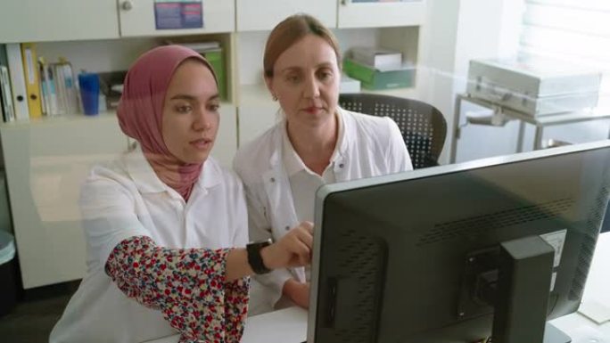 两名医生在ct扫描控制室看电脑监视器