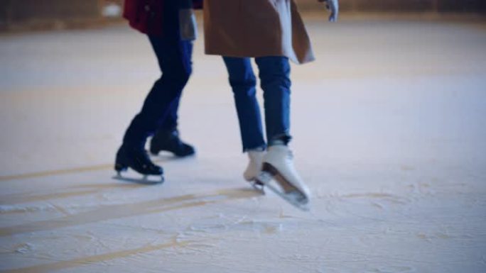 浪漫的冬天下雪的夜晚: 滑冰夫妇在溜冰场上玩得开心。户外双人滑冰。男女朋友培训。中等关注腿部和冰鞋