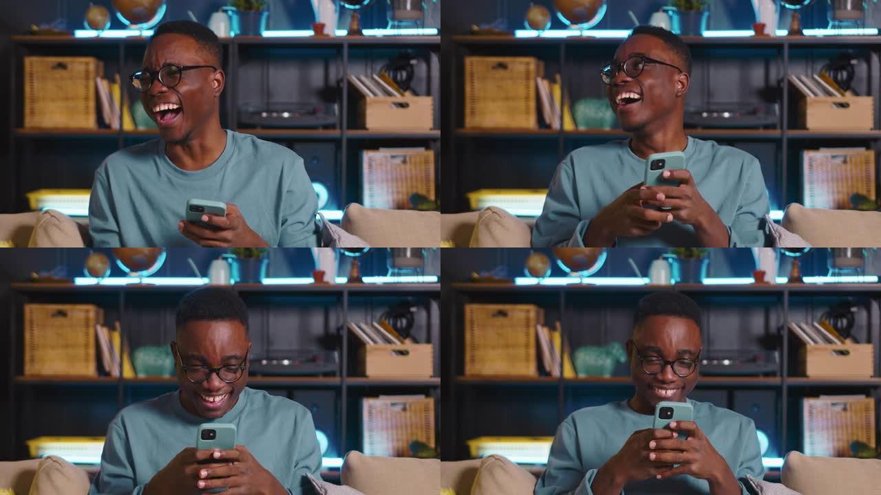 年轻快乐的黑人男学生笑着，在舒适的家中在线社交网络上观看有趣的模因视频。