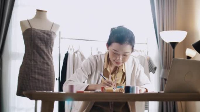 年轻的亚洲女性企业家绘画和设计服装