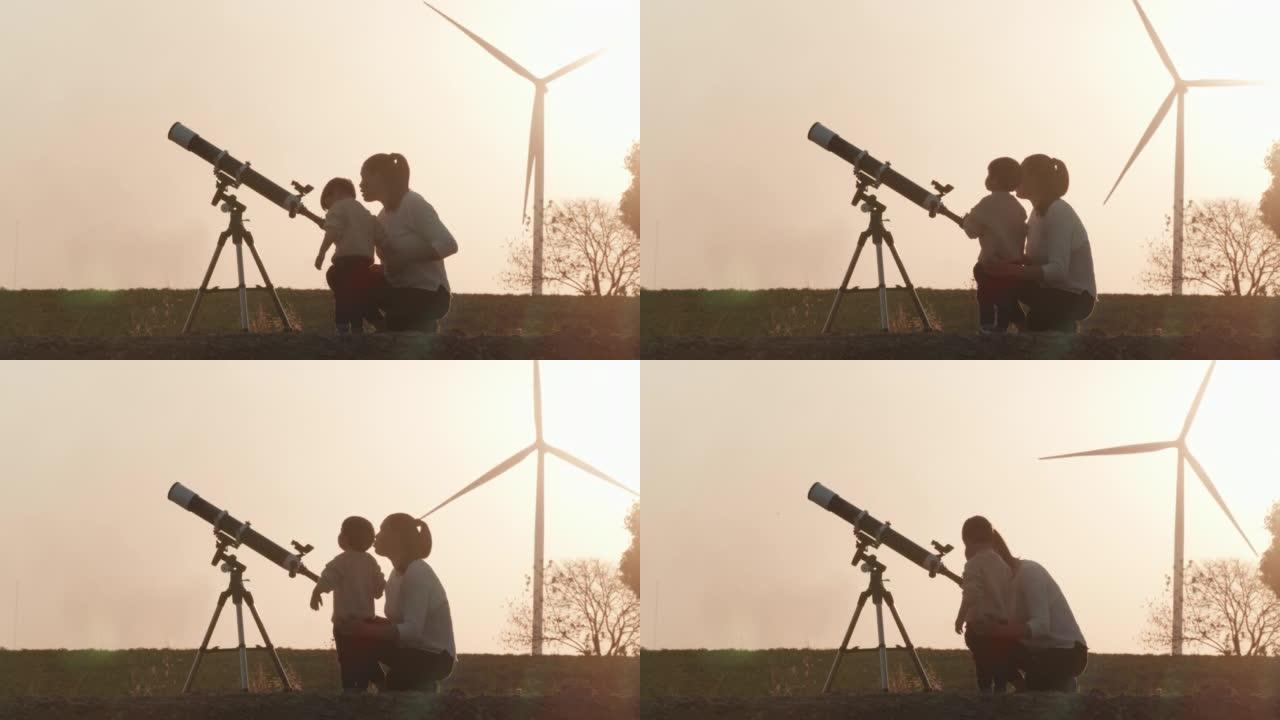 家庭和母亲的剪影日落教学给2岁的男婴使用望远镜一起观察行星和星系，而风力涡轮机回到背景。教孩子们关于