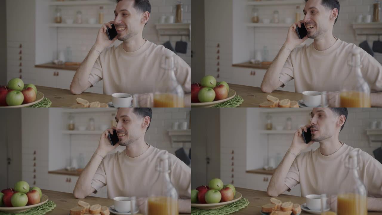 早餐时坐在餐桌上的男人在手机上说话的肖像，厨房里的食物微笑着
