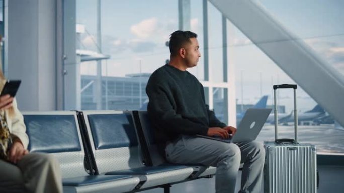繁忙的机场航站楼: 白人妇女使用智能手机，印度商人使用笔记本电脑，等待他的航班。旅行人员使用坐在航空