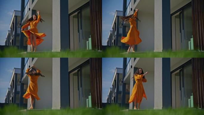 穿着太阳裙的SLO MO年轻女子在她现代房子的露台上旋转