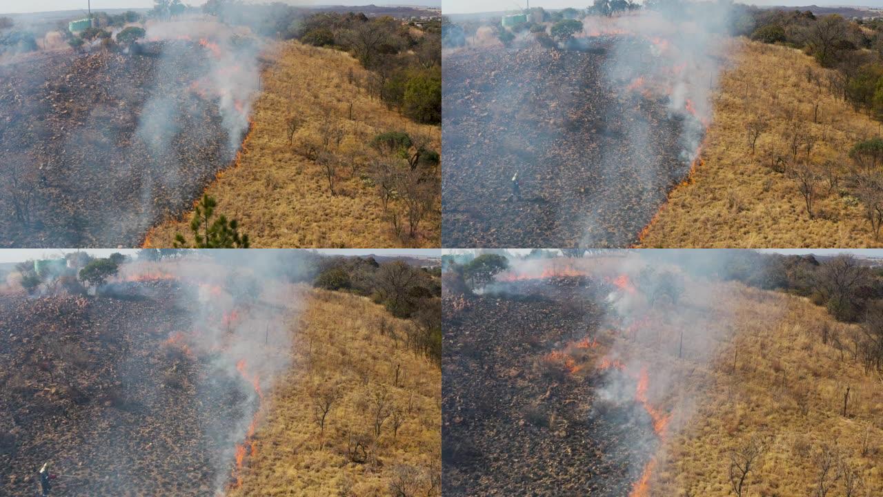 气候紧急情况。一名消防员试图扑灭南部非洲因干旱和气候变化引起的草地大火的鸟瞰图