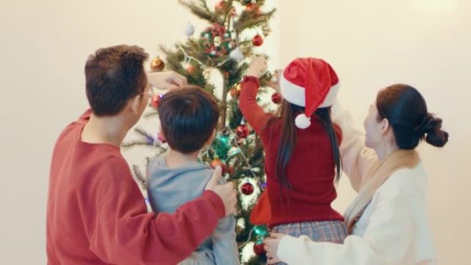 快乐的家庭在装饰圣诞树时玩得开心。