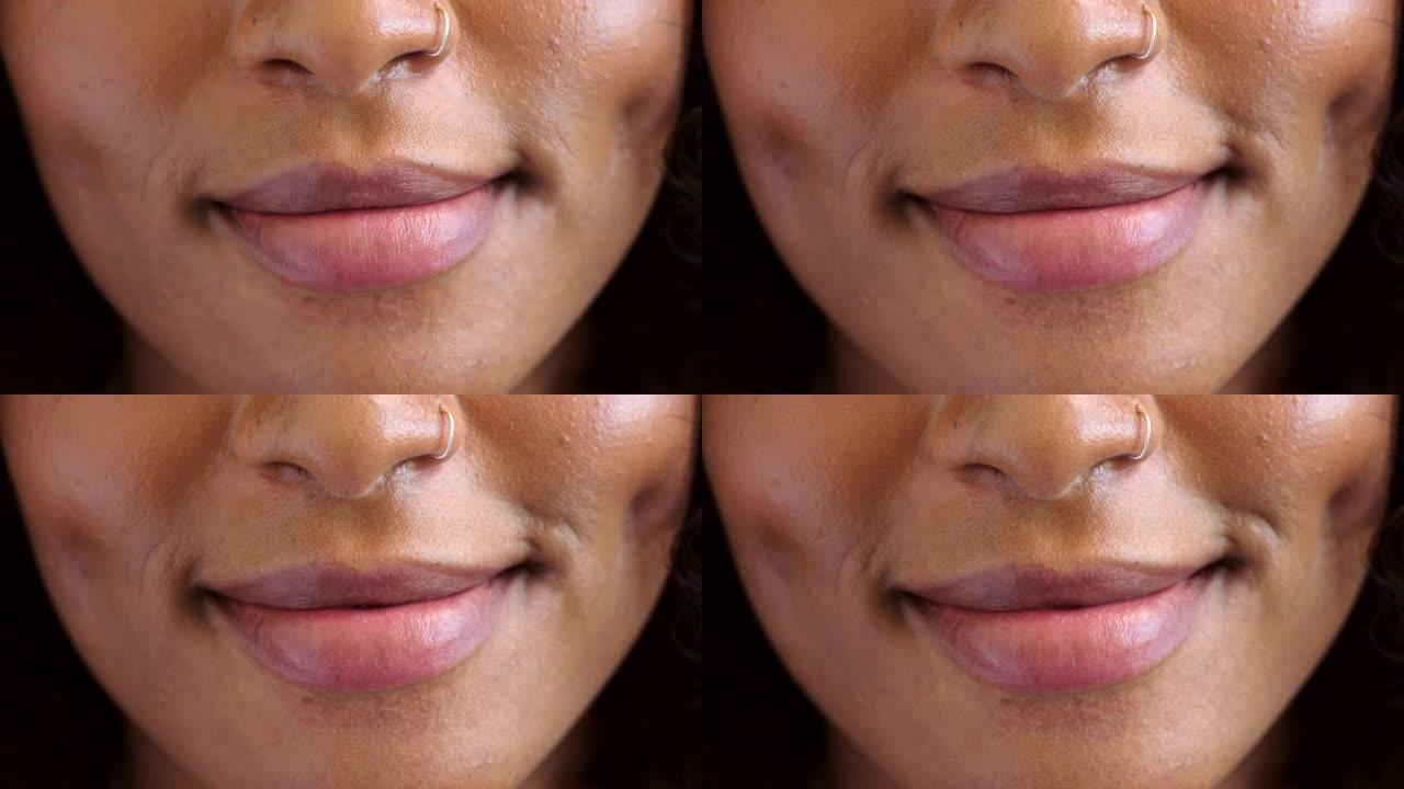 微笑女人的嘴唇在穿着粉红色唇膏，化妆和化妆品时的特写镜头。一个单独站在里面的女人的面部表情友好地微笑