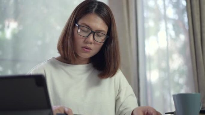 女人在家工作，她的数字平板电脑在家里的客厅