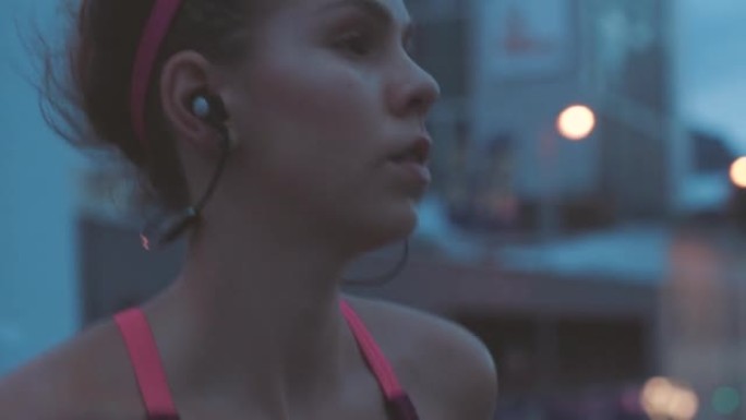 适合晚上在城市里跑步和慢跑的女人。一个认真的年轻运动员在有氧运动和耐力训练时听音乐的特写镜头。为了更