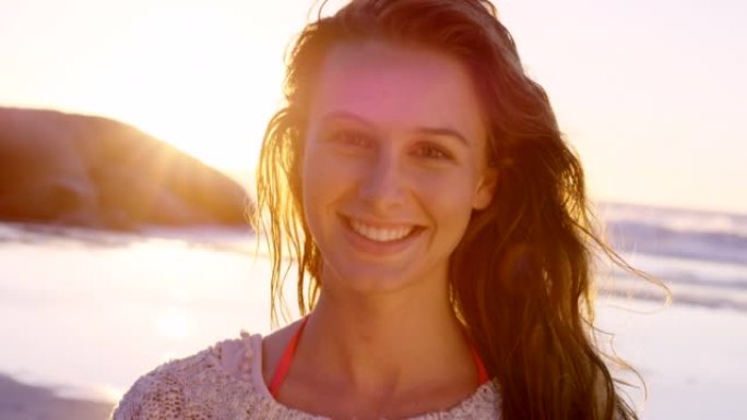4k视频片段，一位迷人的年轻女子在日落时独自站在海滩上