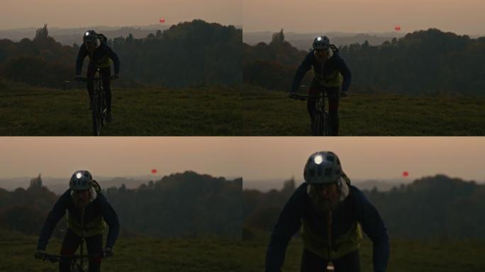 SLO MO Mountain骑自行车的人在黄昏时在乡村骑行时使用头火炬