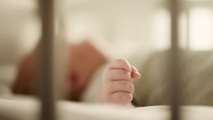 真实的特写镜头，一个可爱的新生婴儿躺在婴儿床的背上。高加索新生儿蹒跚学步的微小人手是焦点。童年、新生