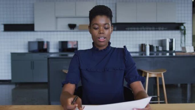 非裔美国女商人在工作场所的厨房里通过文书工作进行视频聊天