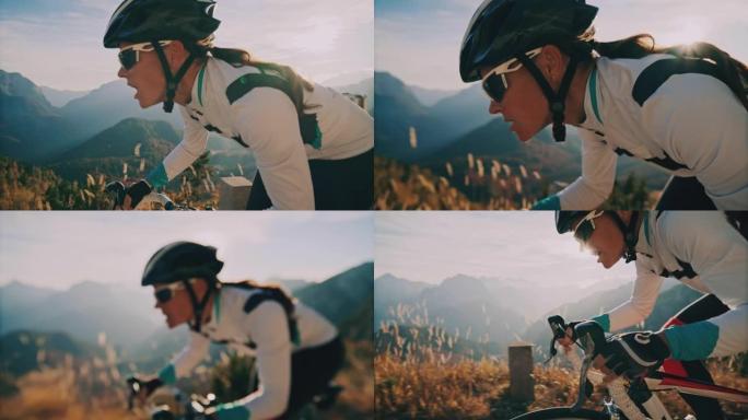 女骑车人在阳光明媚的风景秀丽的山区骑自行车上坡