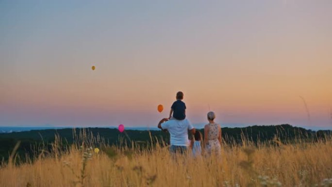 四口之家在太阳落山时在草地上玩气球的慢动作拍摄