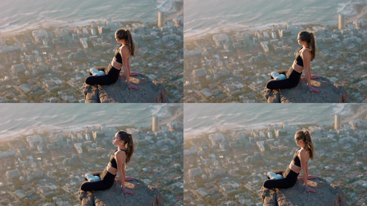山顶上健康的女人在日落时看着平静的海景女孩坐在悬崖边享受自由沉思之旅