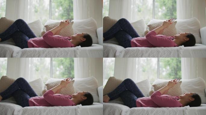 女人躺在家里的沙发上使用智能手机