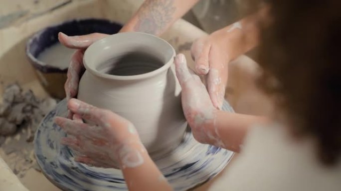 陶器，碗的设计以及儿童学生和老师的手一起用粘土支撑花瓶。创意工作坊，艺术学习和创意设计师班，一个孩子