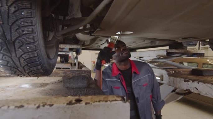 非裔美国机械师检查汽车底部