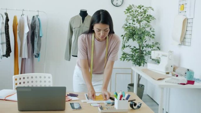 亚洲年轻女装设计师的慢动作为新衣服选择材料和颜色