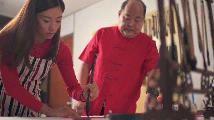 一位亚洲中国男性为即将到来的农历新年庆祝活动而练习中文中文，目的是繁荣和良好的措辞，方法是将其写在红