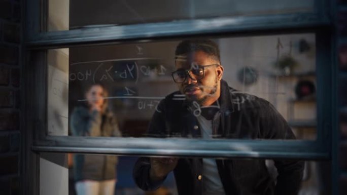 非裔美国年轻人使用可擦除标记来求解窗玻璃上的数学方程式。黑人男导师撰写物理理论并向女学生解释。