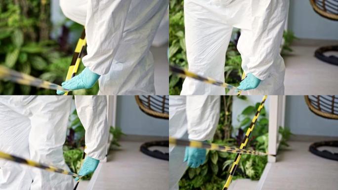 穿着PPE服的慢动作医务人员在感染冠状病毒新型冠状病毒肺炎的患者家中用黄色警告带为隔离和检疫区域设置