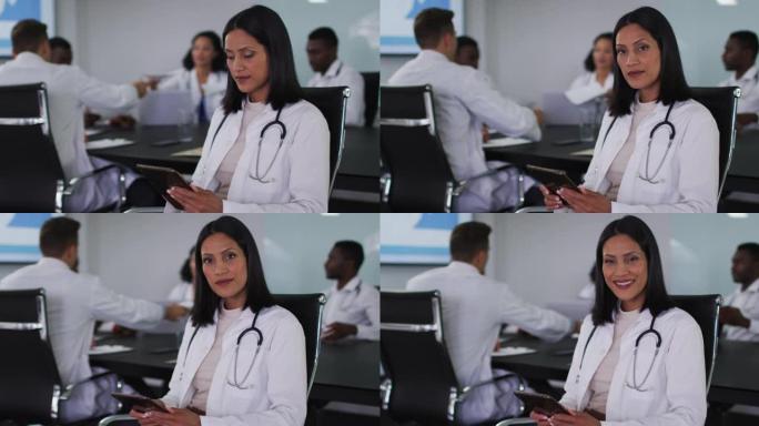混血女医生坐在会议室使用平板电脑微笑