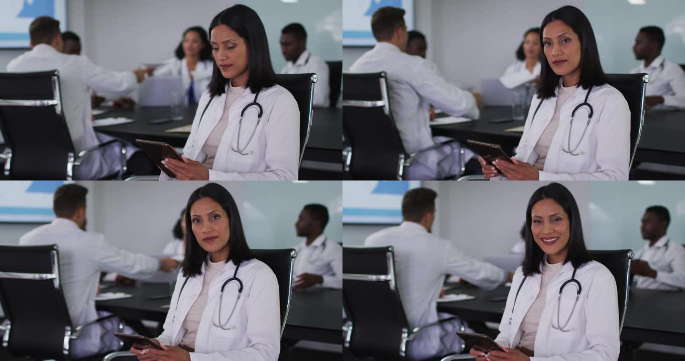 混血女医生坐在会议室使用平板电脑微笑