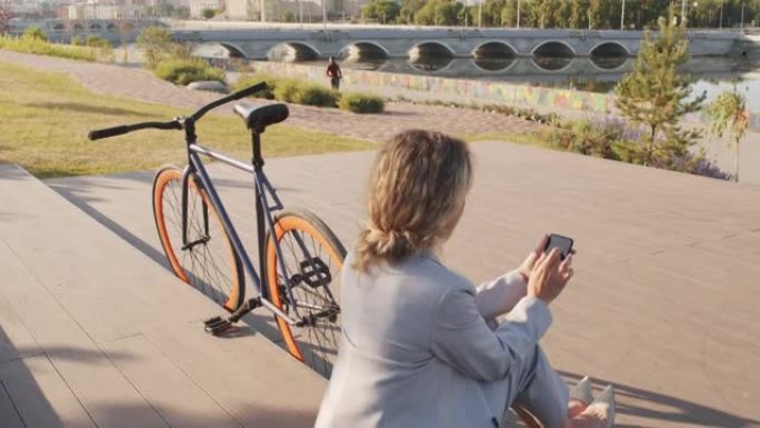 在海滨使用智能手机骑自行车的女商人