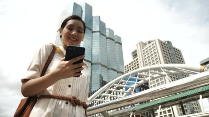 亚洲女商人在使用手机时在城市中行走