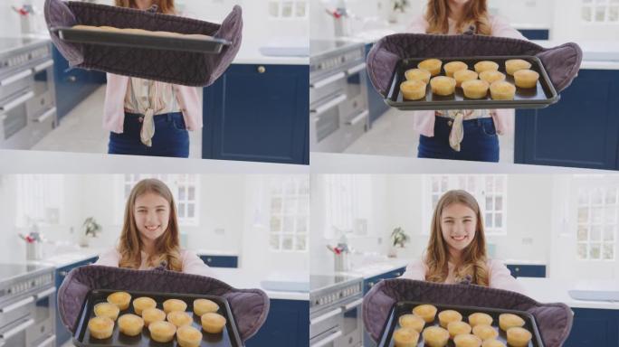 骄傲的少女肖像从家里的烤箱里拿出自制纸杯蛋糕托盘