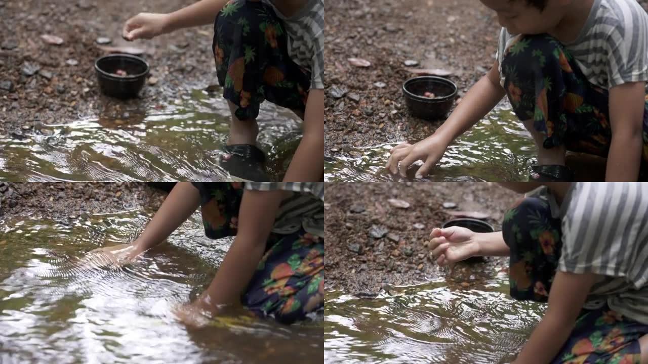 小男孩在小溪里寻找石头。