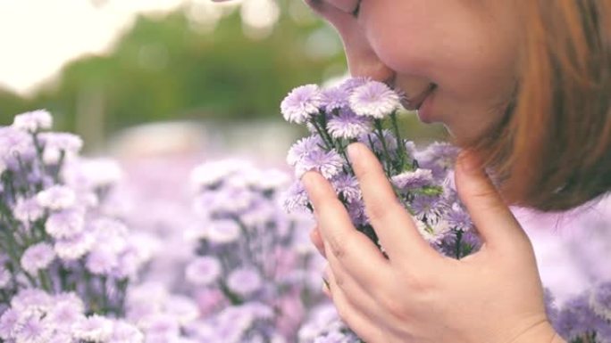 年轻女子幸福，手里拿着紫色的花，在花园里闻到紫色的花