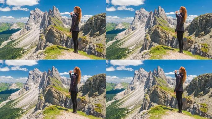 女游客从山上徒步旅行中休息，在史诗般的地方用水瓶喝水