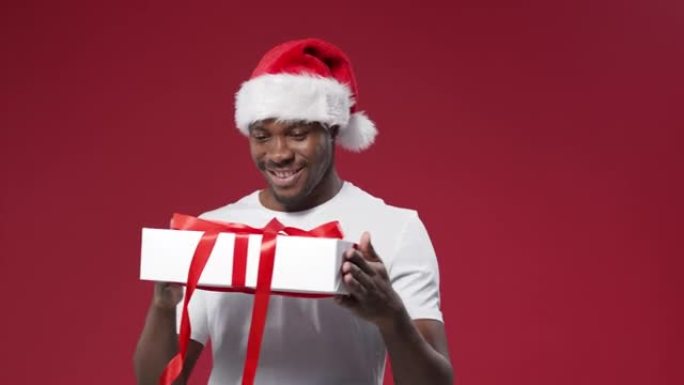一个戴着圣诞帽的黑皮肤微笑的男人转过身，从四面八方看着礼品盒